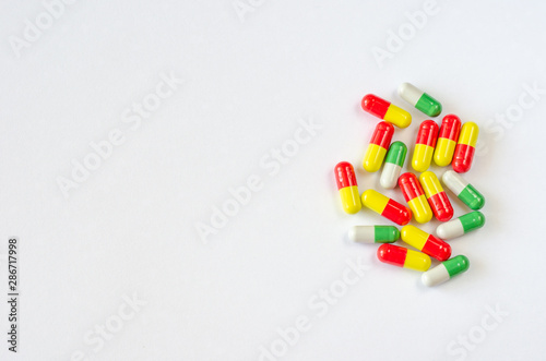 Heap of multi-colored capsules on a white background. Closeup of medicines. Copy space. Top view