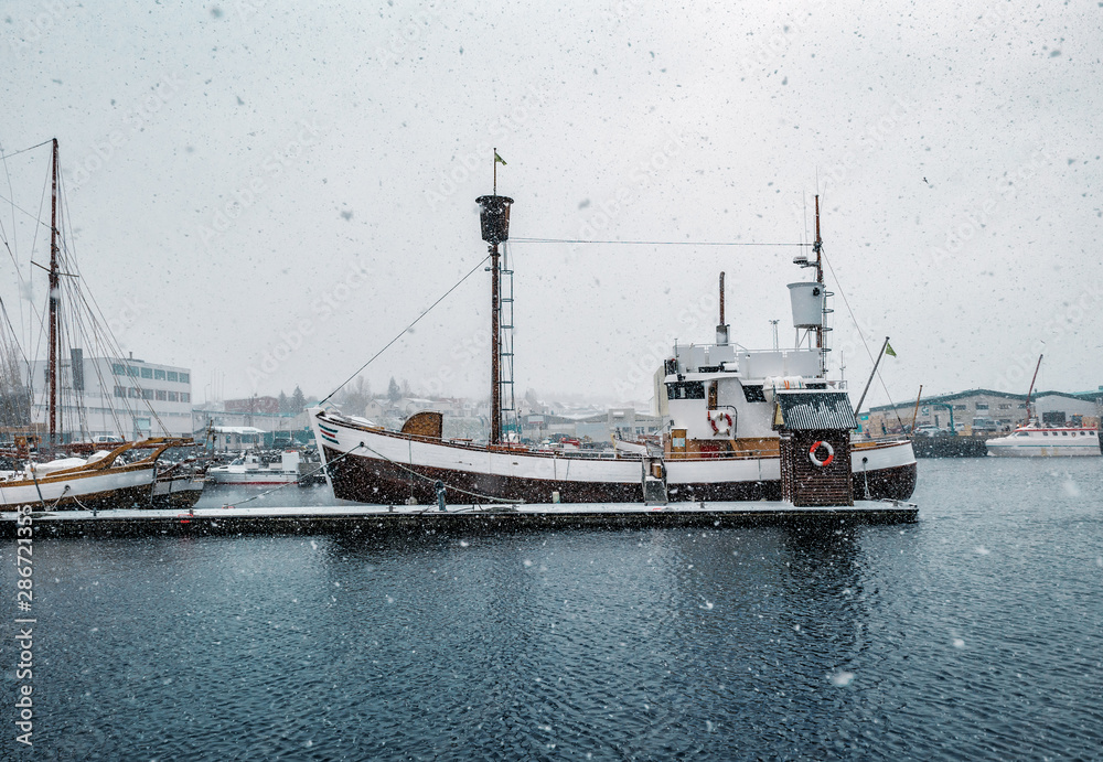 Naklejka premium fishing boat in port and snowstorm