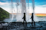 two girls walking under a waterfall