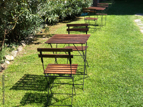 Wooden chairs and tables on green grass in park  © Kate