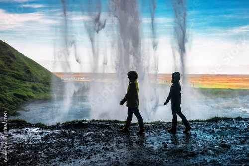 two girls walking under a waterfall photo