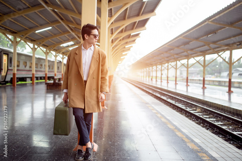 Portrait business man fashion at train station. Traditional train for transportation. Travel concept.