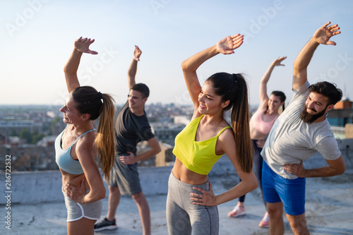 Group of fit happy sporty people exercising outdoors