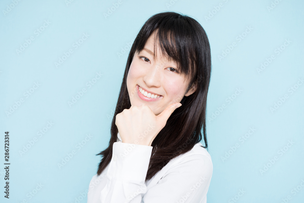 Young business woman giving thumb up gesture against light blue background Young business woman giving thumb up gesture against light blue background