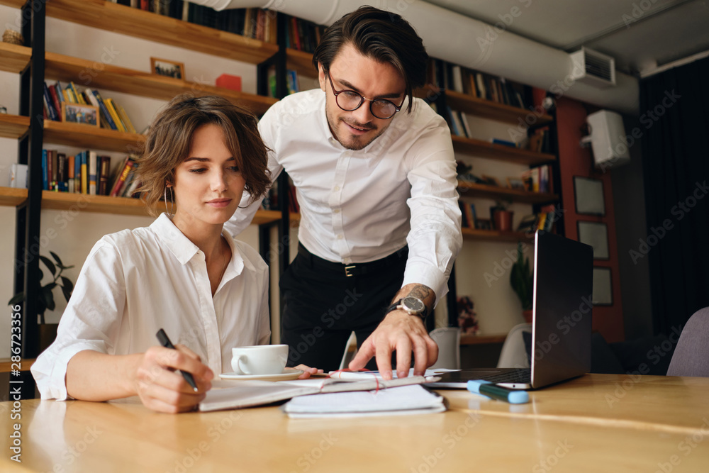 Young attractive business colleagues dreamily working on new project with laptop in office Young attractive business colleagues dreamily working on new project with laptop in office
