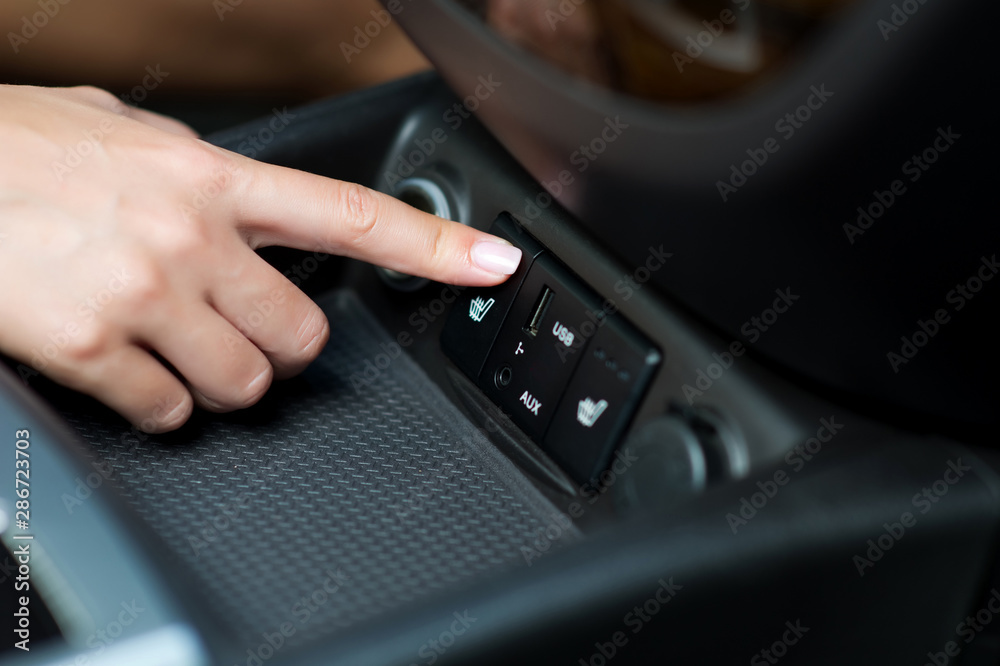 woman's hand turns on seat heating in the car woman's hand turns on seat heating in the car