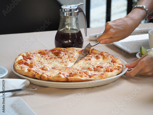 Close up of a woman taking a piece of pizza in a restaurant.