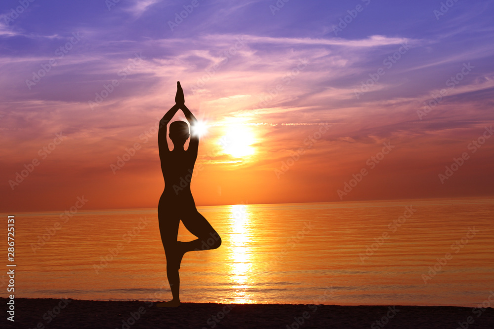 Silhouette of Woman Meditating in Yoga pose by the Sea at Sunset. Nature Meditation Concept. Low key photo. relax time