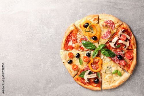 Delicious pizza with different pieces on grey background, space for text