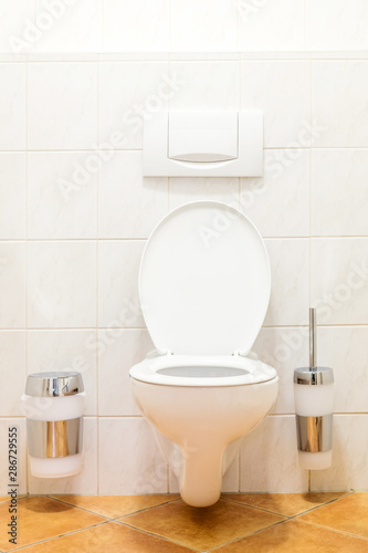 Clean, white toilet and paper rolls with tiles wall