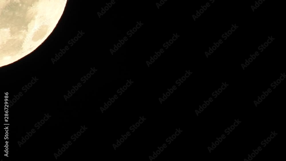 Close-up super zoom, golden half moon crossing the night sky