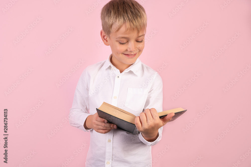 Boy reading a book thirsty for knowledge - isolated over pink background Boy reading a book thirsty for knowledge - isolated over pink background