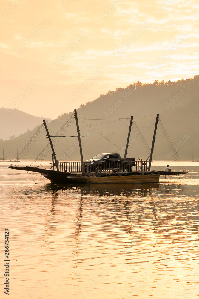 Local wooden ferry boat on peaceful lake at sunset.