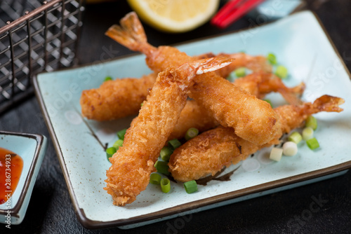 Close-up of deep-fried shrimps in breadcrumbs on a turquoise plate, selective focus, studio shot