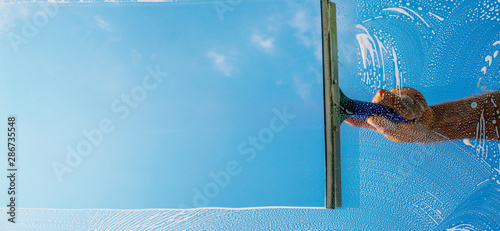 Fensterputzer putzt Fenster mit Schaum und Abzieher Panorama