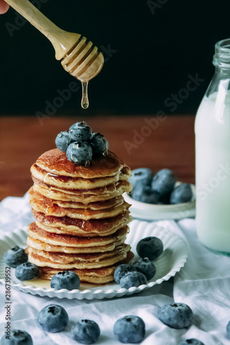 Blueberry pancake Homemade  and pouring  honey stick with milk  for  breakfast on wood table.Vertical photos