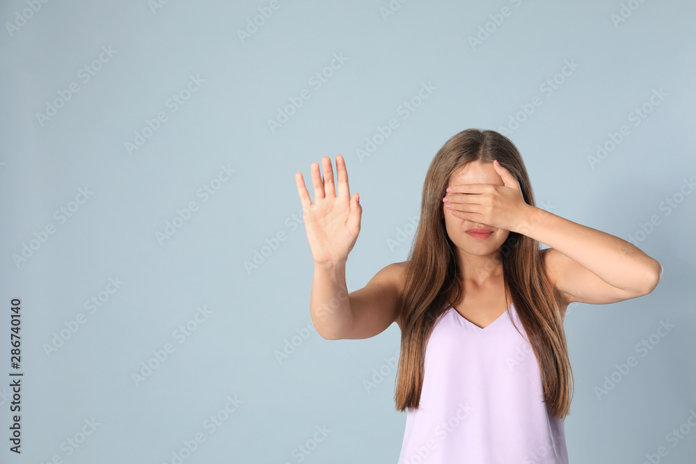 Young woman being blinded on grey background, space for text
