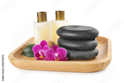 Wooden tray with spa stones, orchid flowers and bottles on white background