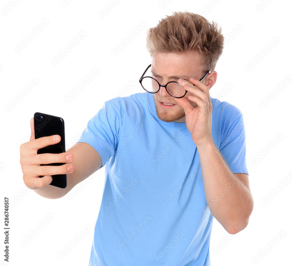 Young man with glasses using mobile phone on white background. Vision problem