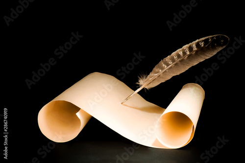 Unrolled scroll of papyrus with a pen on a black background