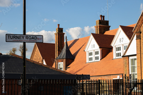 19th century old school building and modern sign of street name are in London, UK, Dulwich area. It is a bright sunny day. This school successfully operates and in our days.