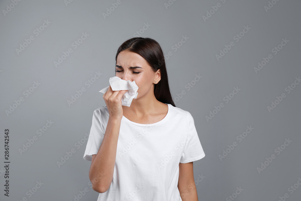Young woman suffering from allergy on grey background Young woman suffering from allergy on grey background