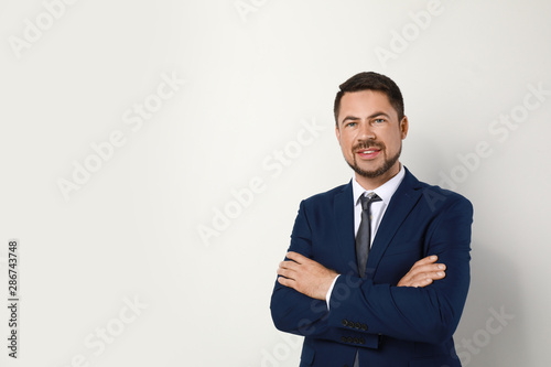 Portrait of handsome man in suit on light background. Space for text
