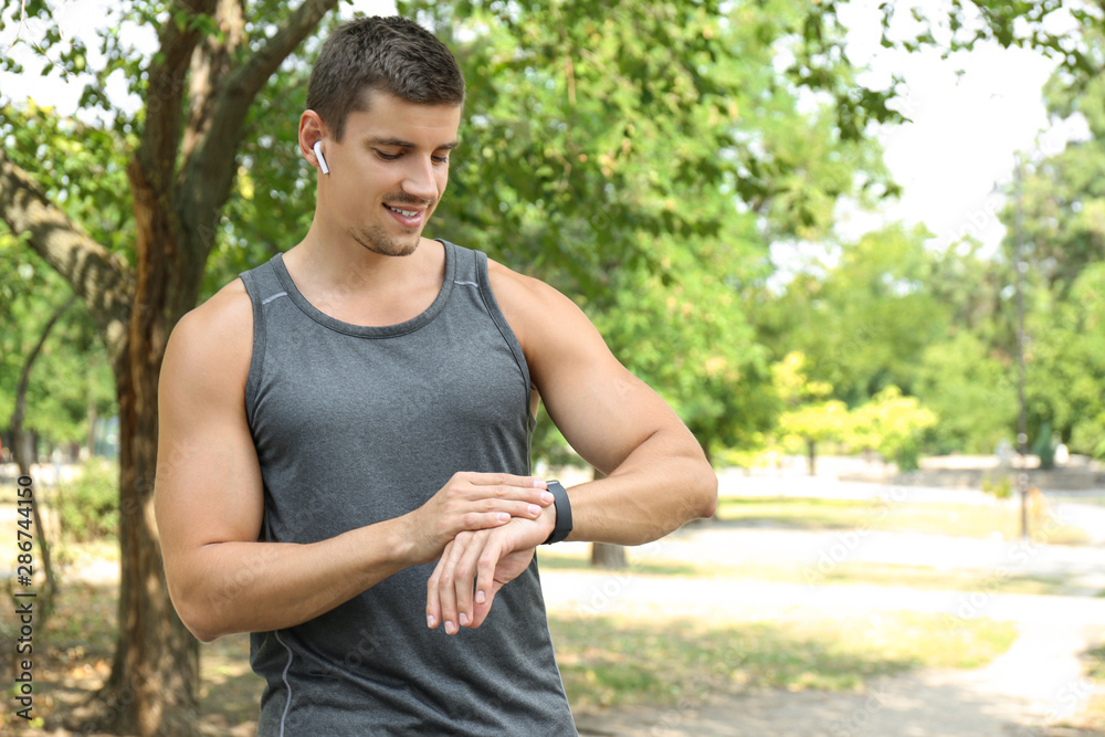 Young man checking pulse with smartwatch after training outdoors Young man checking pulse with smartwatch after training outdoors