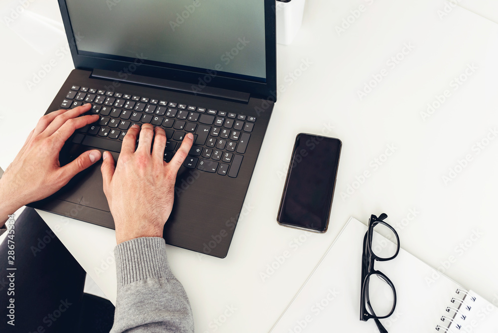 Man using laptop computer while sitting at desk in office. Top view. Overhead shot. Man using laptop computer while sitting at desk in office. Top view. Overhead shot.