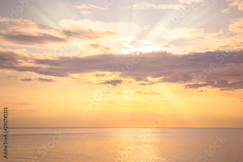Calm sea with sunset sky and sun through the clouds over. Meditation ocean and sky background. Tranquil seascape. Horizon over the water.