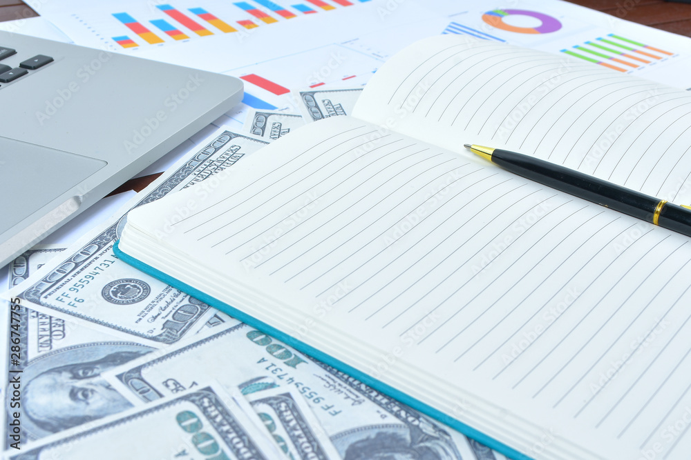Business Concept. Laptop, graph and banknote dollars with notebook and pen Business Concept. Laptop, graph and banknote dollars with notebook and pen