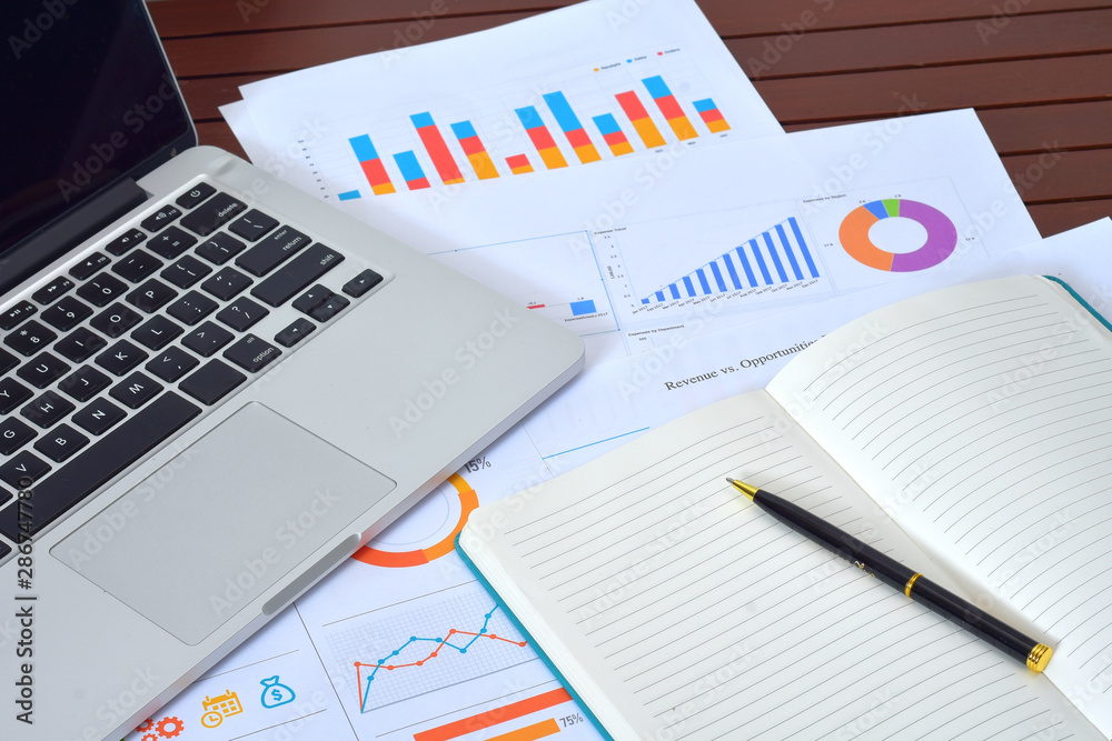 Business and Finances Concepts. Laptop, Notebook with graph and pen Business and Finances Concepts. Laptop, Notebook with graph and pen