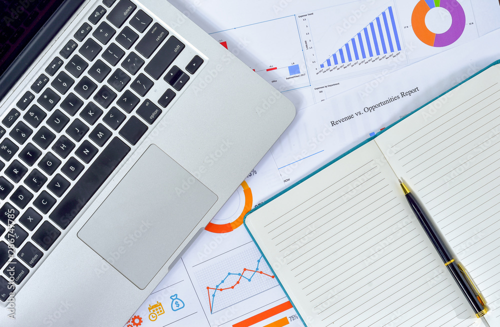 Business and Finances Concepts. Laptop, Notebook with graph and pen Business and Finances Concepts. Laptop, Notebook with graph and pen