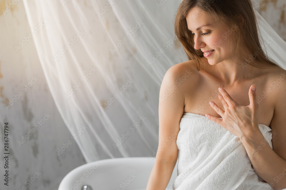 Naklejka premium beautiful young woman in towel sits in a bath