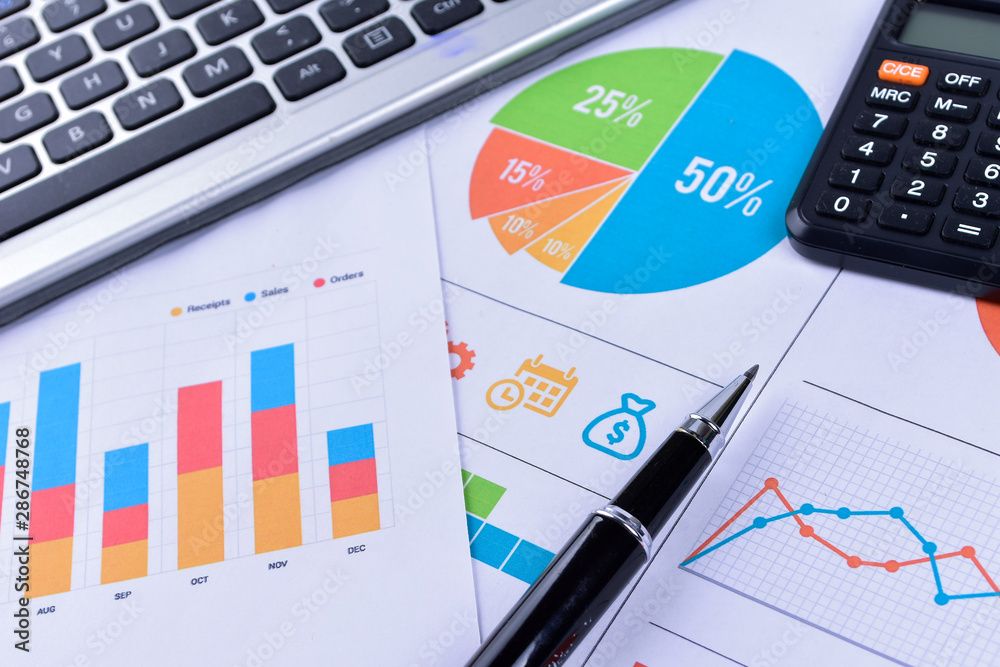 Laptop and pen with business charts, graphs, statistic and documents background for education and business concepts Laptop and pen with business charts, graphs, statistic and documents background for education and business concepts