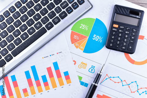 Laptop and pen with business charts, graphs, statistic and documents background for education and business concepts