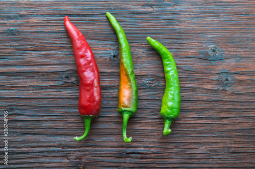 Three hot peppers on a wooden table. View from above.