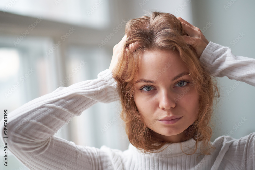 Fototapeta premium portrait of a beautiful curly girl. the mysterious face of a woman at the window.