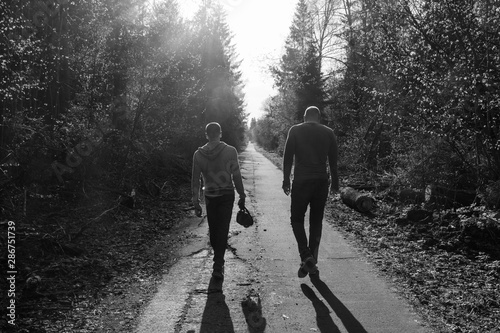 Two friends are walking along the alley, sad mood, atmosphere of quarrel or resentment; black and white photo