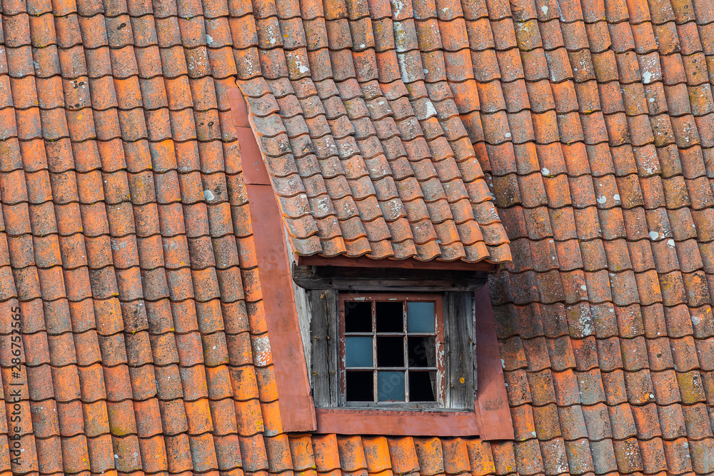 old pitched red tile roof with tiny garret casement widows. Window on the roof. old pitched red tile roof with tiny garret casement widows. Window on the roof.