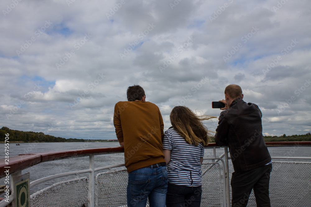 a girl and two guys backs on the bow of the ship