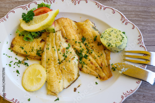Stampa su tela fried plaice fillet with herb butter and lemon on a plate, typical food in north