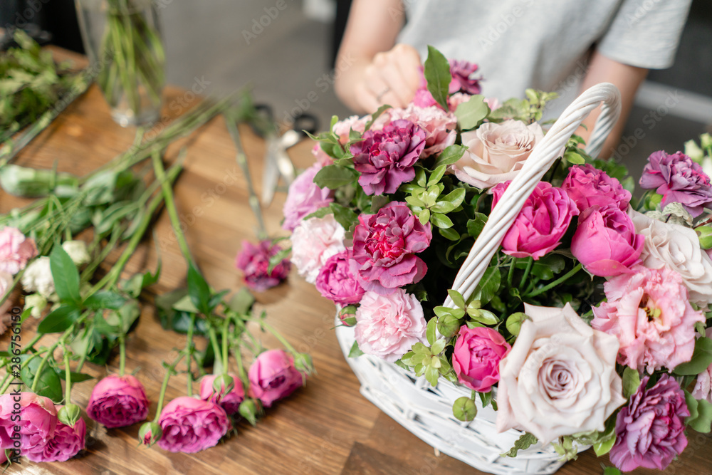 Woman florist create flower arrangement in a wicker basket. Beautiful bouquet of mixed flowers. Floral shop concept . Handsome fresh bouquet. Flowers delivery