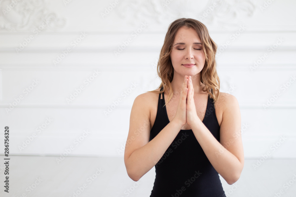 Smiling woman meditates holding hands on her chest. Empty space for text Smiling woman meditates holding hands on her chest. Empty space for text