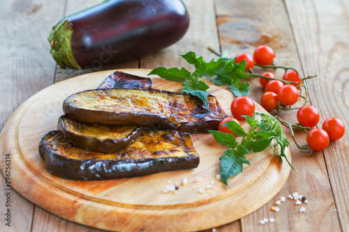 Delicious roasted eggplant and homemade cherry tomato on a wooden board. Healthy vegetarian food.