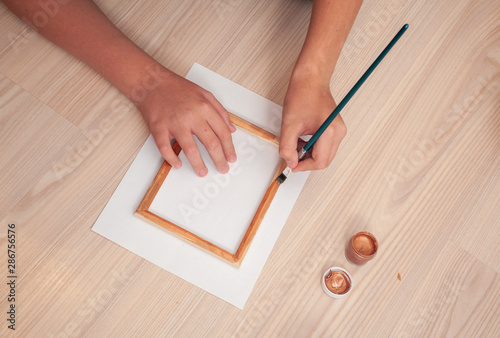 Hand with brush paint wooden door frame in bronze color top View Flat lay