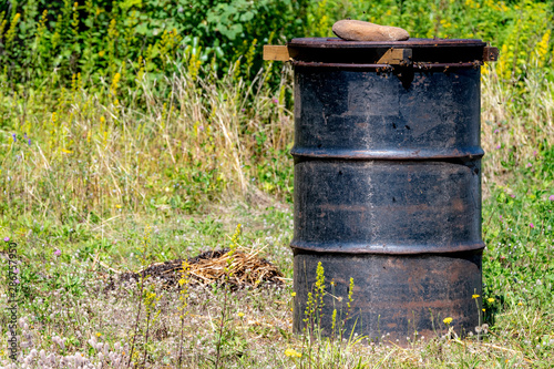 A black barrel being used as a bee feeder. Barrels containing sugar syrup are used as inexpensive bee feeders at beehive farms.