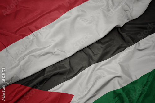 waving colorful flag of palestine and national flag of indonesia.