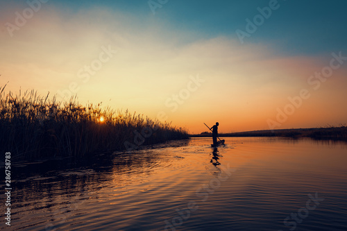 Man poling in dugout canoe at sunset along the Cuando river
