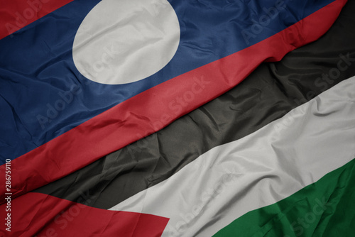 waving colorful flag of palestine and national flag of laos.